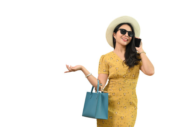 白色背景下，一名穿着夏日连衣裙、戴着太阳镜的快乐女子微笑着打电话。图片下载