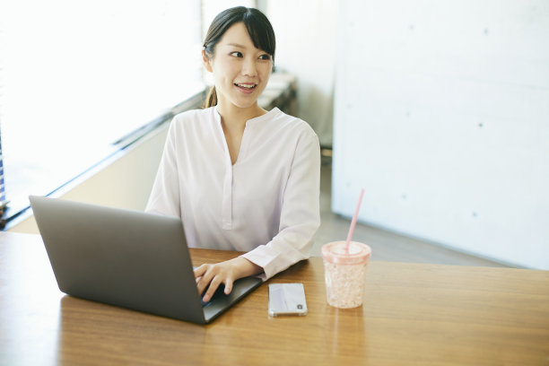 年轻的亚洲女人在靠窗的办公室工作图片下载