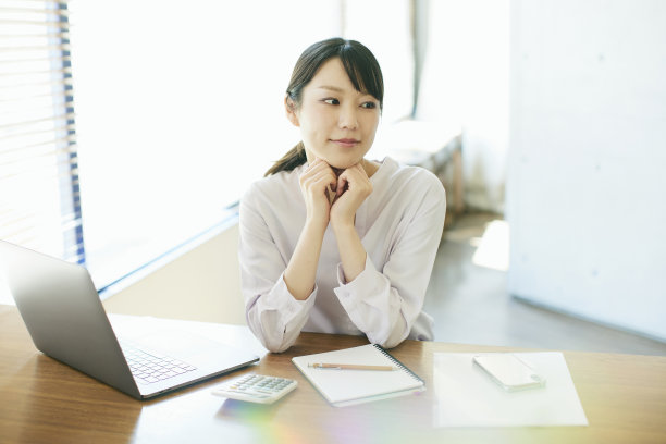 年轻的亚洲女人在靠窗的办公室工作图片下载