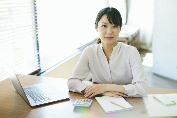 年轻的亚洲女人在靠窗的办公室工作图片下载