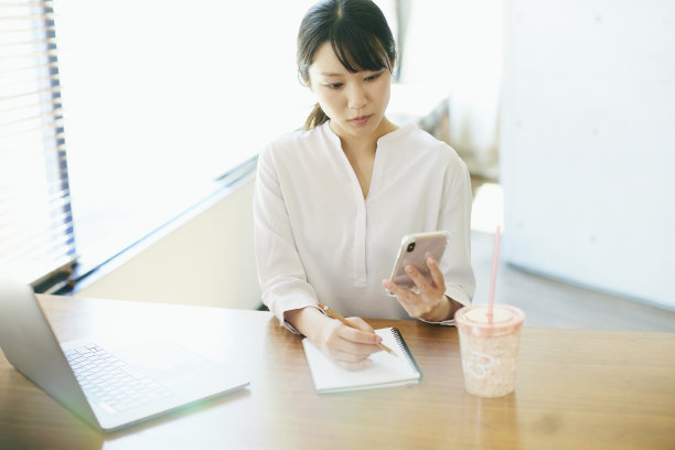 年轻的亚洲女人在靠窗的办公室工作图片下载