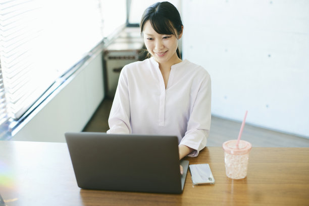 年轻的亚洲女人在靠窗的办公室工作图片下载