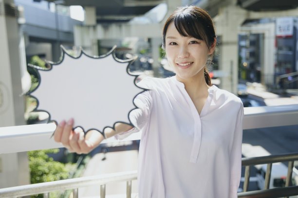 一名亚洲妇女在人行天桥上举着一个空的演讲泡泡。图片下载