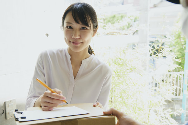 一名日本女子从快递员那里收到包裹。图片下载