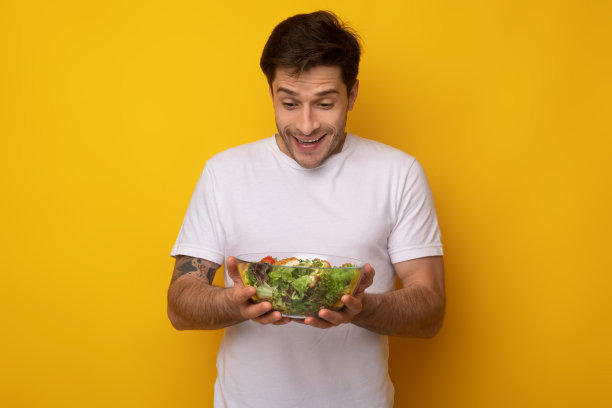 微笑的男人拿着盛有沙拉的碗图片下载