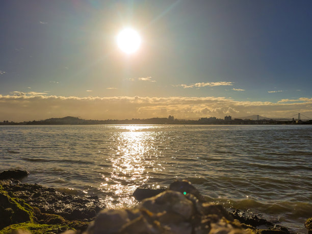 傍晚时分的照片，太阳即将落山，大海和一些岩石图片下载