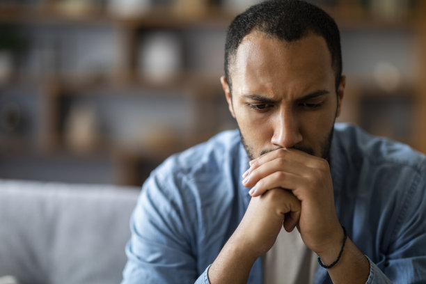 在家沙发上沉思的年轻黑人男人特写肖像图片下载