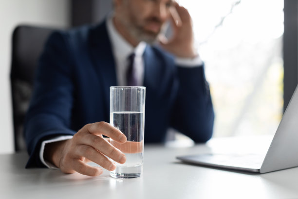 压力大的商人在工作场所头痛，手里拿着一杯水图片下载