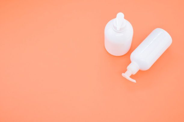 橙色背景上白色塑料瓶的高角度拍摄图片下载