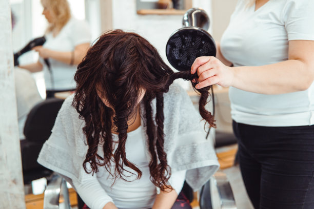 理发师在沙龙吹干顾客的头发图片下载