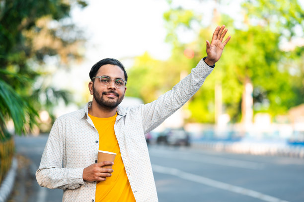 年轻人拿着一杯咖啡在路上等公交车或出租车图片下载