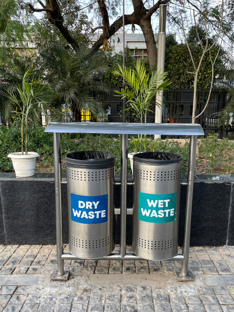 近距离图像的圆柱形，金属垃圾桶在隔间在公园，干湿垃圾箱塑料袋内衬桶在金属框架与屋顶，重点在前景图片下载