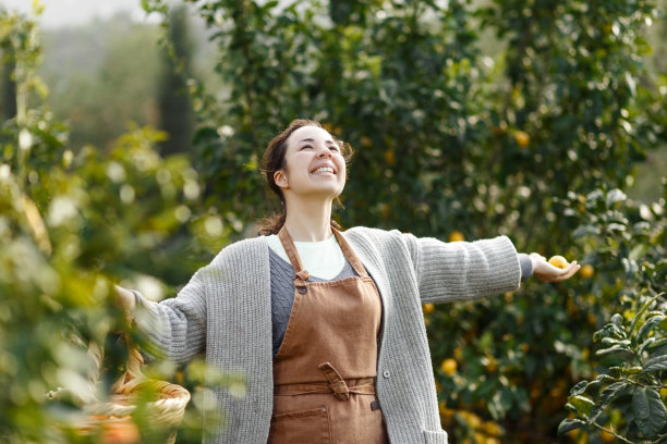 来自橘子农场的女农民。园丁把橘子收集到篮子里。微笑的农民在农贸市场上拿着新鲜的橙子出售。橘子农场经营理念。图片下载