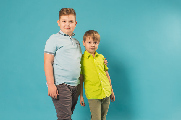 两个男孩在蓝色背景的工作室图片下载