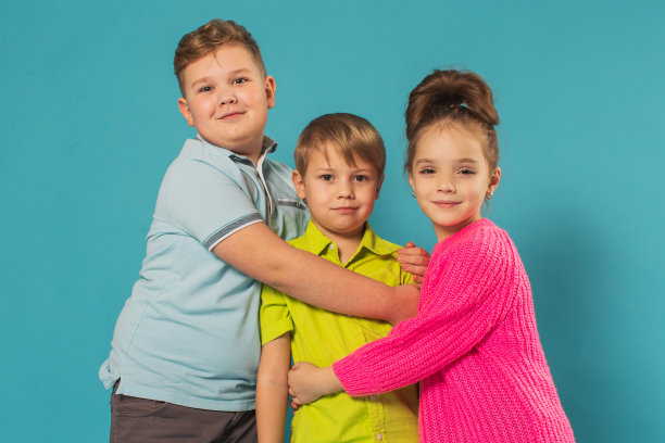 两个男孩和女孩在蓝色背景的工作室图片下载