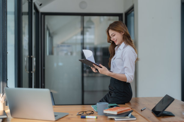 年轻的亚洲妇女站在办公桌前阅读文件的肖像图片下载