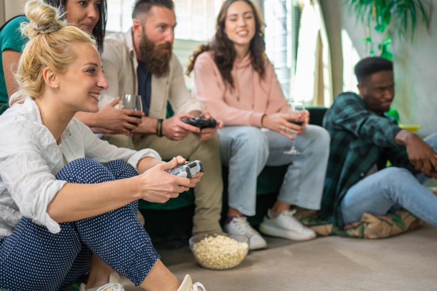 五个一组的朋友在玩电子游戏，专注于金发女孩的脸，手里拿着控制器图片下载