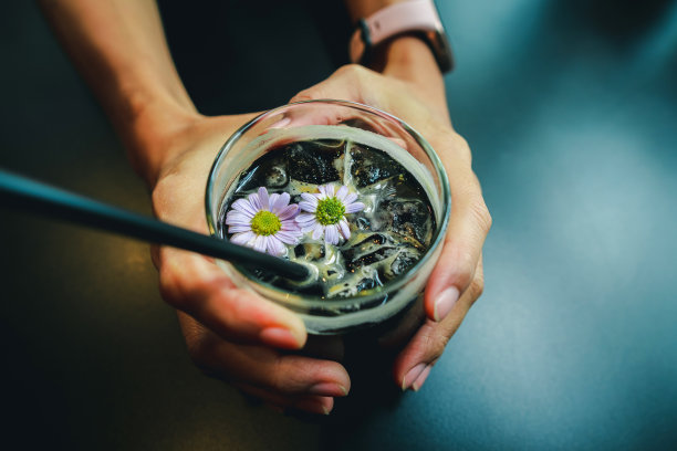 在咖啡馆里，一个女孩手里端着一杯黑咖啡图片下载