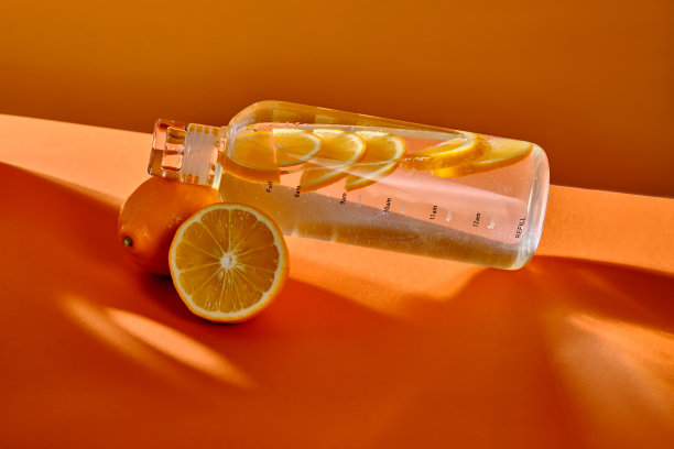 橙色背景柠檬玻璃水瓶。图片下载