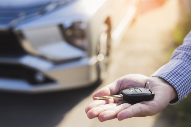 一个商人拿着车钥匙在孤立的背景和修剪路径图片下载