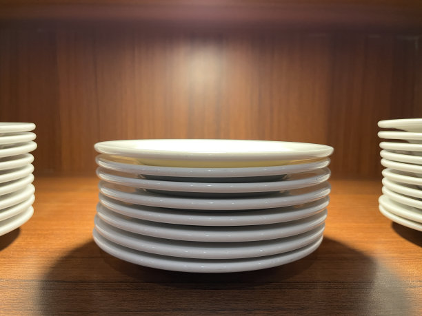 一堆白色的盘子在一个有聚光灯的木柜子里图片下载