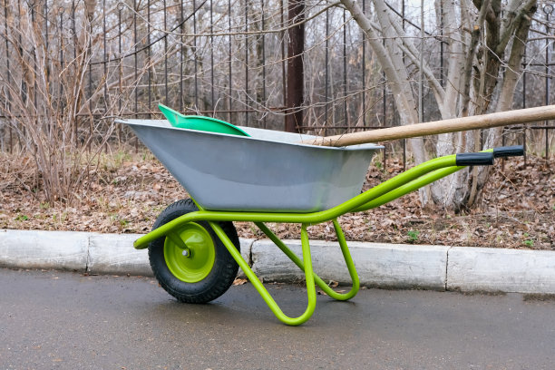 院子里有一辆轮子明亮的花园手推车。工作花园用具图片下载