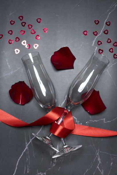 顶部视图香槟酒杯与红丝带，玫瑰花瓣和小心形图片下载