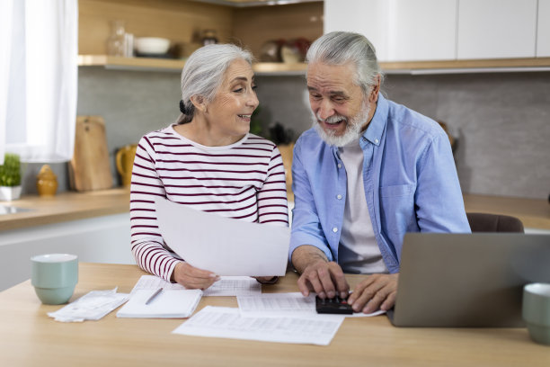 快乐的老年配偶坐在厨房里查看财务文件的照片图片下载