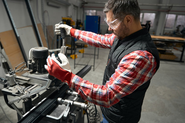 一个成年男子在车间的机器前工作图片下载