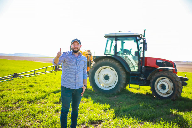 年轻的农民在一辆红色拖拉机前用手做了一个勾图片下载