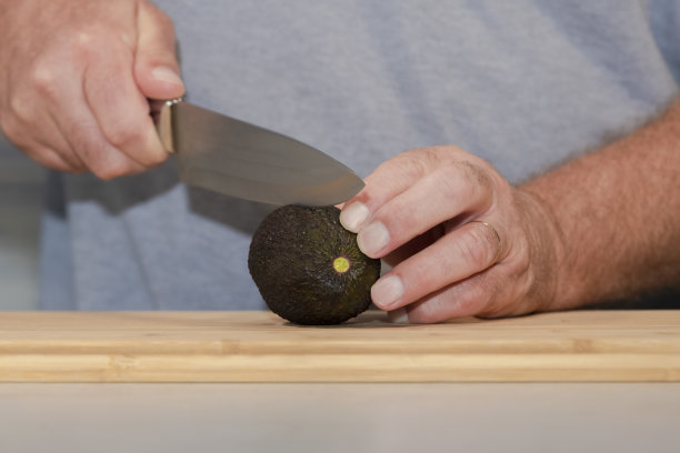 一个男人在木板上切牛油果的特写图片下载