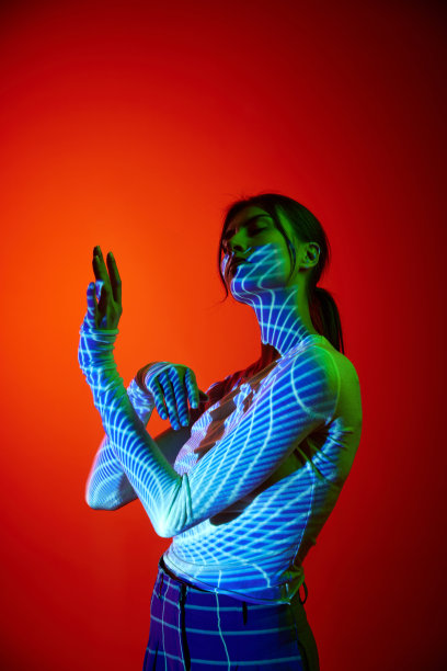 年轻美丽的女人的肖像与数字霓虹灯滤光的身体在红色背景。艺术、时尚、赛博朋克、未来主义和创意的概念图片下载