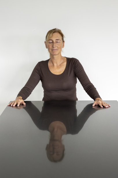 一个金发扎马尾的中年妇女的肖像，她身后有一扇带有白色墙壁的窗户图片下载