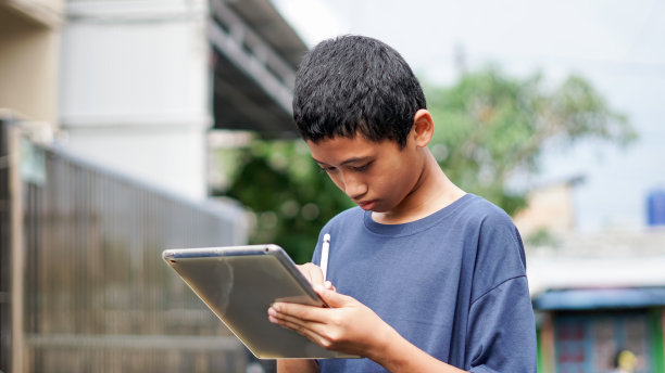 亚洲男孩在户外使用平板手机图片下载