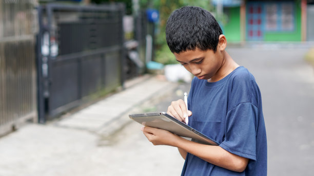 亚洲男孩在户外使用平板手机图片下载