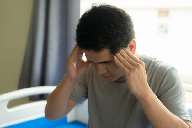 头痛的亚洲男人坐在床上，保健概念。图片下载