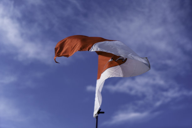 旗帜在蓝白色的天空下飘扬图片下载