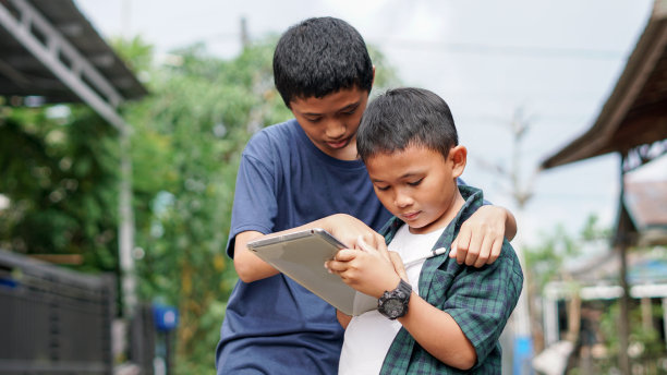 亚洲男孩和兄弟在户外使用平板手机图片下载