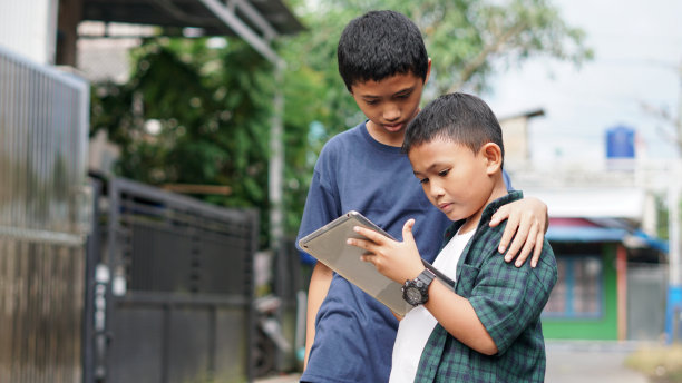 亚洲男孩和兄弟在户外使用平板手机图片下载