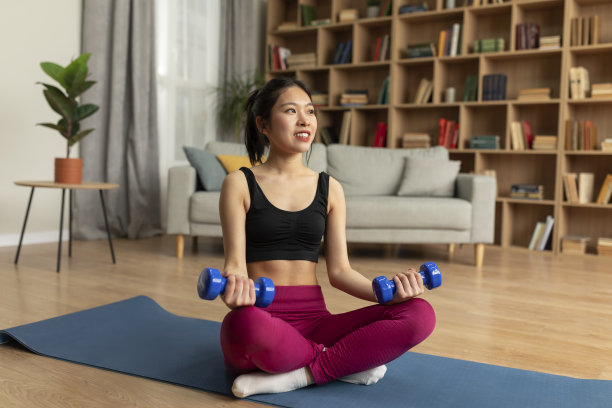 健身亚洲女士在运动服装做力量练习哑铃，坐在瑜伽垫，有国内训练图片下载