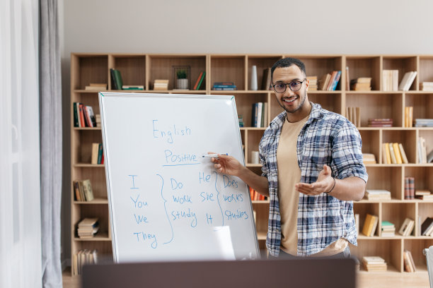 在线教育愉快的阿拉伯男性教师指着白板和解释英语语法规则的肖像图片下载