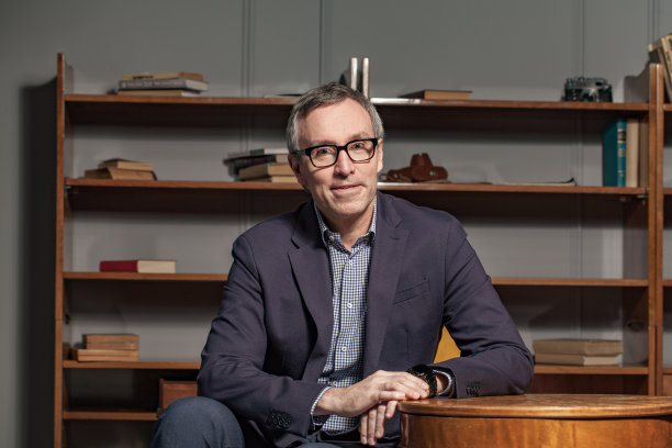 穿着蓝色西装、戴着眼镜的成熟商人正坐在办公室里图片下载