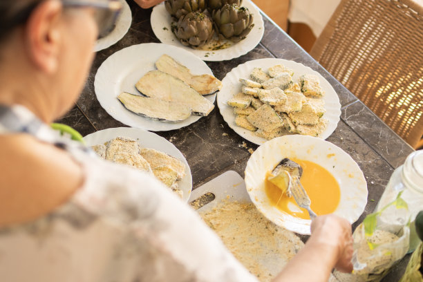 女人用鸡蛋、面粉和面包屑给蔬菜裹上面包屑图片下载