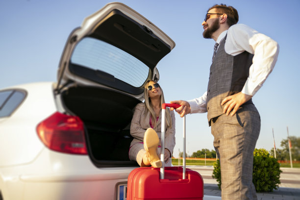 有趣的场景，女人坐在汽车后备箱里，腿放在行李箱上的男人站在旁边。难伺候的女人图片下载