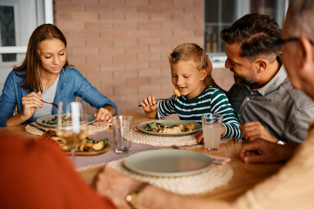 快乐的男孩和他的家人在阳台的餐桌上吃午饭。图片下载