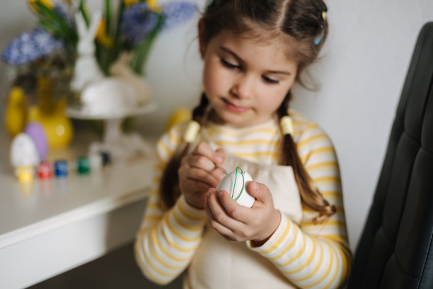 复活节在家，可爱的小女孩在厨房画彩蛋。关注手图片下载