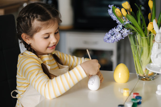 小女孩在厨房画鸡蛋的过程。春天的节日。家里的复活节装饰。侧视图图片下载