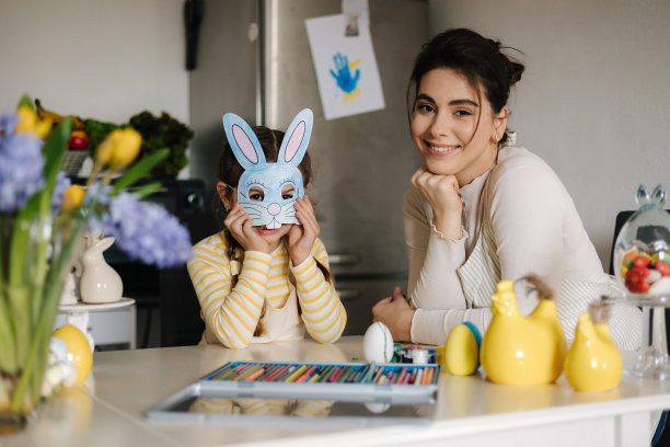 可爱的小女孩戴上了复活节兔子面具。快乐的妈妈在微笑。假期图片下载