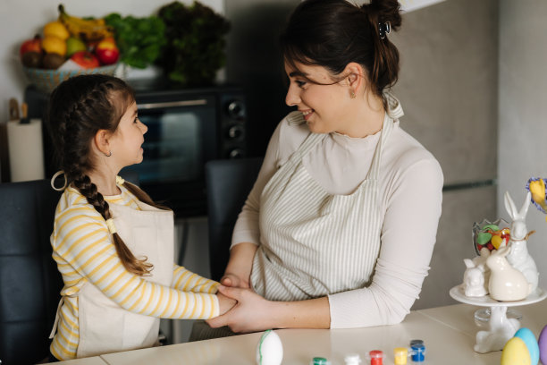 可爱的小女孩和她的妈妈准备画复活节彩蛋。妈妈和女儿互相看着对方图片下载