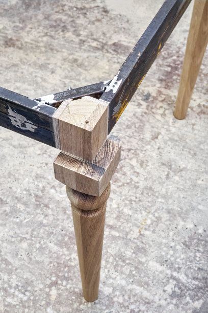 在车间制造桌子时，雕刻腿上的金属桌架图片下载